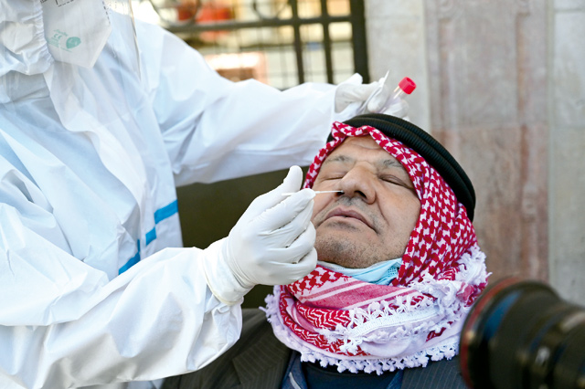 A healthcare worker uses a swab to collect sample from a man during a coronavirus test in Amman in these recent photograph (Photo by Amjad Ghsoun)