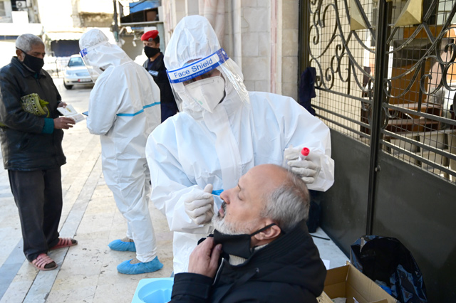 A healthcare worker uses a swab to collect sample from a man during a coronavirus test in Amman in this recent photograph (Photo by Amjad Ghsoun)
