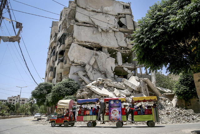 Syrian children tour in a train around the collapsed buildings near the children’s park, installed by the civil defence during Eid Al Fitr at Arbin town in Damascus, Syria, on Tuesday (Anadolu Agency photo)