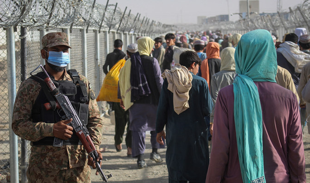A Pakistani soldier stands guard as Afghans walk along fences after arriving in Pakistan through the Pakistan-Afghanistan border crossing point in Chaman on August 26, 2021 (AFP file photo)