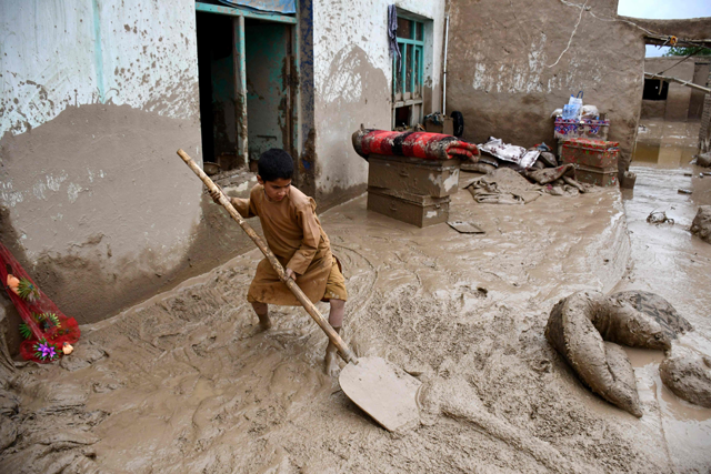 An Afghan boy shovels mud from the courtyard of a house following flash floods after heavy rainfall at a village in Baghlan-e-Markazi district of Baghlan province on Saturday (AFP photo)
