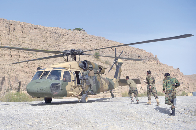 In this photograph taken on March 25, Afghan national army  soldiers unload food items and petrol oil from an Afghan Air Force Black Hawk helicopter at the hydroelectric Kajaki Dam in Kajaki, northeast of Helmand province, Afghanistan (AFP photo)