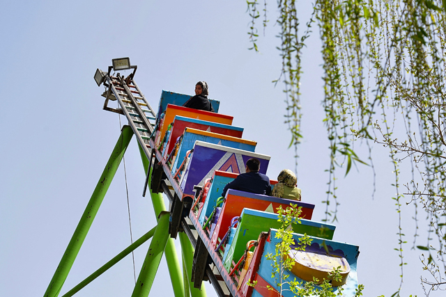 An Afghan girl along with other people enjoy a ride on a swing at an amusement park in Kabul, on Monday  (AFP photo)