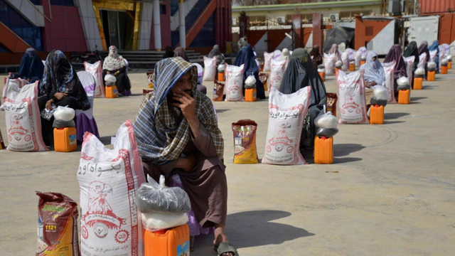 Afghan women sit next to food aid distributed by a charity foundation during the Muslim holy fasting month of Ramadan in Kandahar on March 28 (AFP photo)