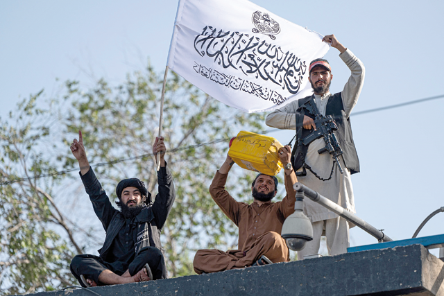 A Taliban security personnel holds a dummy yellow canister intended to be containing homemade explosives, while sitting with fellow personnels at the security tower of the vacated US embassy compound in Kabul on Tuesday (AFP photo)