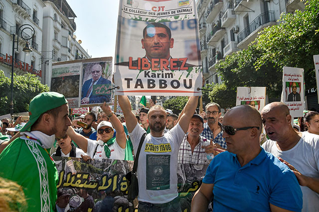 In this file photo taken on Tuesday, an Algerian protester marches with a sign calling for the liberation of opposition figure Karim Tabbou during a demonstration against the ruling class in the capital Algiers (AFP photo)