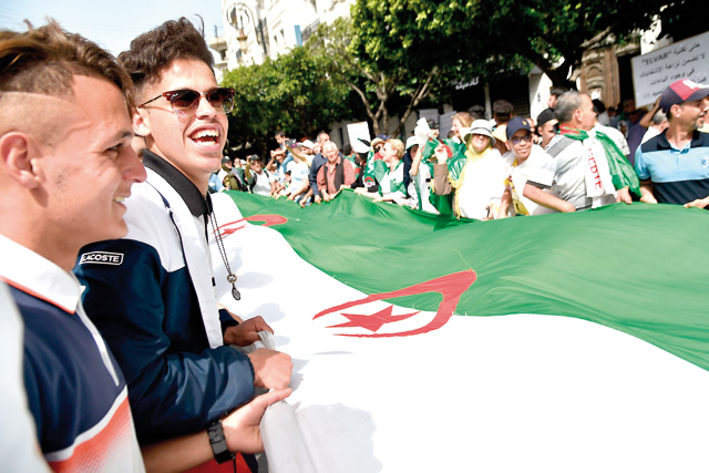 Algerian protesters hold the national flag as they demonstrate in the capital Algiers, on Friday (AFP photo)