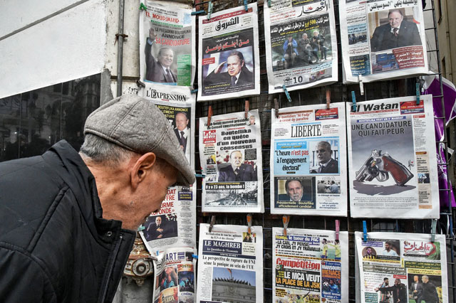 An Algerian looks at the headlines of newspapers at a kiosk in the capital Algiers on Monday, writing about the upcoming presidential election scheduled for April 18 (AFP photo)
