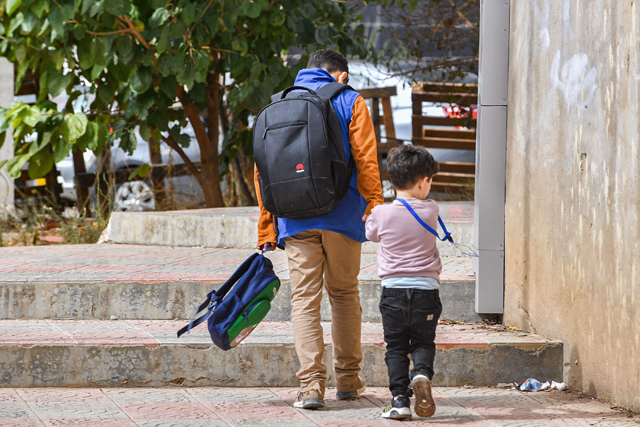 A child is escorted back home from school by his guardian in Algeria’s capital Algiers, on Tuesday (AFP photo)