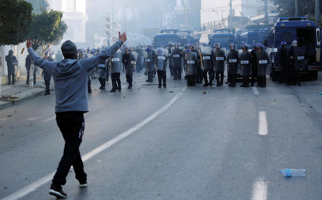 A protester confronts police, who used tear gas to disperse crowds, as people marched to protest against President Abdelaziz Bouteflika's plan to seek a fifth term, in Algiers, Algeria, on Friday (Reuters photo)