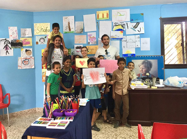 Zaid Souqi poses for a group photo with children who participated in an art activity recently (Photo courtesy of the Orenda Tribe)