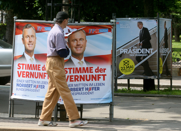 In this picture taken on May 19, a man walks past election posters of Alexander van der Bellen, candidate for the presidential elections and former head of the Austrian Greens (right) and Norbert Hofer, candidate for presidential elections of Austria’s right-wing Freedom Party (left), in Vienna, Austria (AP photo)