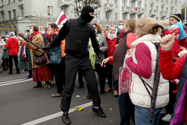 Belarusian pensioners argue with a law enforcement officer during a rally to demand the resignation of authoritarian leader and new fair election in Minsk, on Monday (AFP photo)