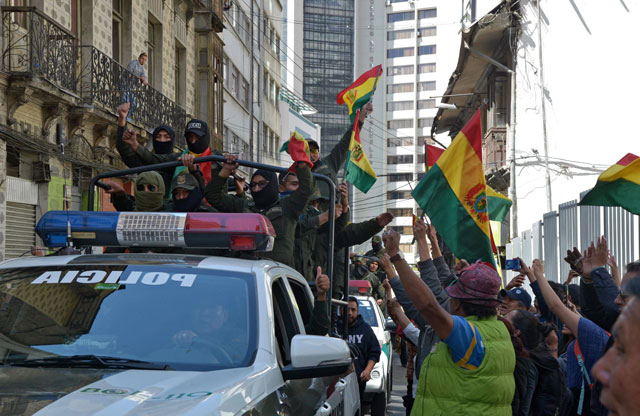 People cheer as officers of the Police Special Operations Tactical Unit (UTOP in Spanish) displaying Bolivian flags head to their headquarters at the Plaza de Armas in La Paz, on Saturday (AFP photo)