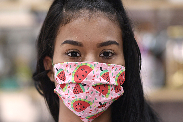 A young woman wears a protective mask against the spread of the new Coronavirus (COVID-19) made by seamstresses of the Vila Novo Sao Lucas favela (AFP photo)
