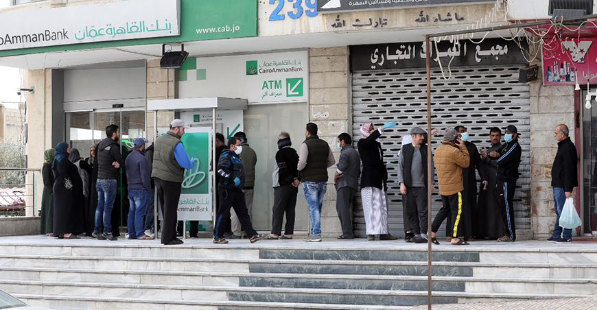 People wait in line outside a bank in Amman on Monday, as a decision by the Central Bank of Jordan extends working hours for banks and money exchanges (Photo by Osama Aqarbeh)