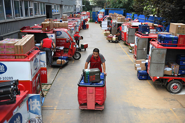 A worker hauls packages to delivery carts at a JD.com distribution centre in Beijing on Thursday (AFP photo)