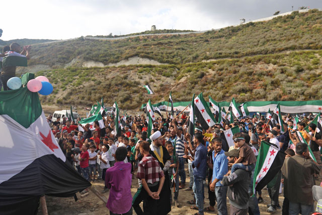 Syrians gather in demonstration under a Turkish army border post, near the town of Khribat Jawz on the Syrian-Turkish border, on Friday (AFP photo)