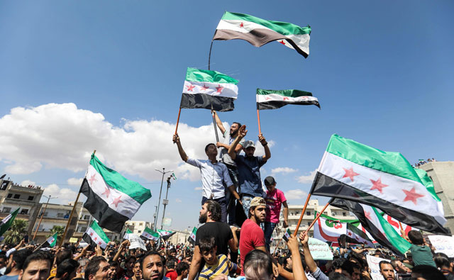 Syrians from the rebel-held northern city of Idlib and its surrounding towns wave the flag of the opposition and chant slogans as they gather for an anti-government demonstration in a main square in Idlib on Friday (AFP photo)