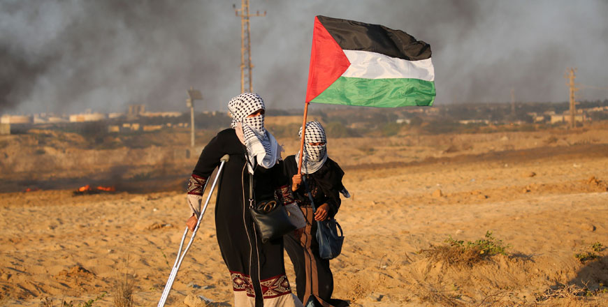 Palestinian demonstrators carry a national flag during a protest calling for an end to the Israeli blockade on Gaza, on a beach in Beit Lahiya near the maritime border with Israel, on Monday (AFP photo)
