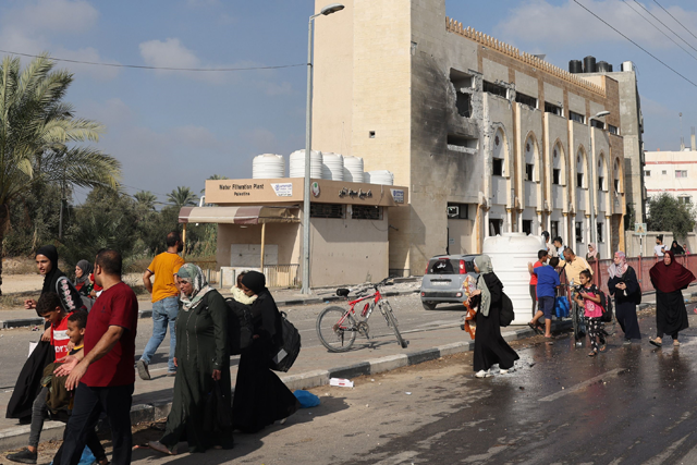 Palestinians walk past a damaged mosque as they flee Gaza City and other parts of northern Gaza towards the southern areas on Wednesday (AFP photo)