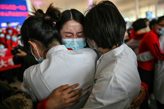 A medical worker leaving Wuhan hugs colleagues before boarding a plane back home (AFP photo)