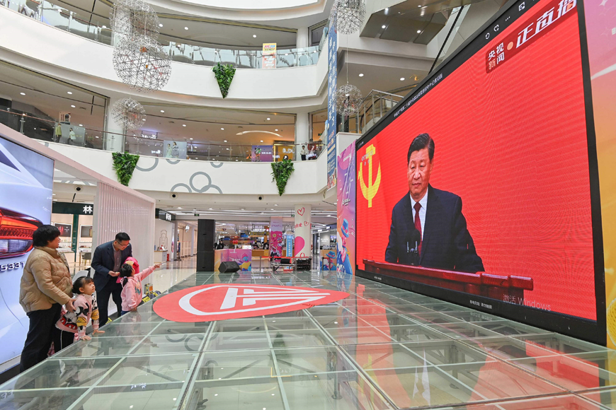 People watch a live broadcast of China's President Xi Jinping speaking during the introduction of the Communist Party of China's Politburo Standing Committee, on a screen at a shopping mall in Qingzhou in China's eastern Shandong province, on Sunday (AFP photo)
