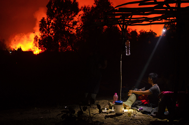 In this photo taken on October 10, a man monitors a forest fire outside of his relative's house as a fire approaches in Ogan Ilir, South Sumatra (AFP photo)