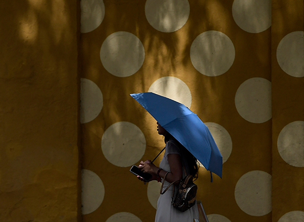 A pedestrian uses an umbrella while walking during a heatwave in Seville on Monday (AFP photo)