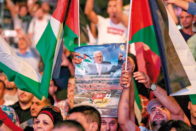 Palestinians wave Palestinian flags and photo of President Mahmoud Abbas during a demonstration in a square in the West Bank city of Ramallah, ahead of his speech during the 73rd Session of the UN General Assembly in New York, on Thursday (AFP photo)