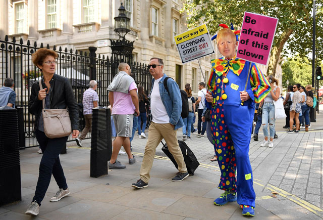 A demonstrator, dressed as a clown and wearing a mask of Britain's Prime Minister Boris Johnson, protests outside the gates to Downing Street on Whitehall in London on Tuesday (AFP photo )