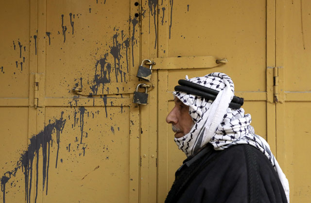 A Palestinian man walks past a closed shop in the southern West Bank city of Hebron after the Palestinian Fateh political party called a general strike over Israeli settlement activity in the area, on Monday (AFP photo)