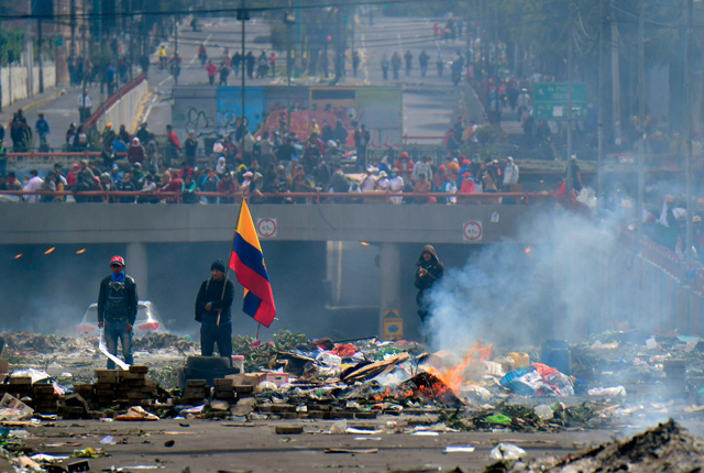 People stand in the street amid the rubble, following a 10-day protest over a fuel price hike ordered by the government to secure an IMF loan, in Quito, on Saturday  (AFP photo)