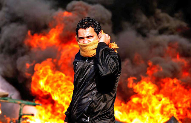 A protester stands in front of a burning barricade during a demonstration in Cairo, on January 28, 2011 (Reuters photo)