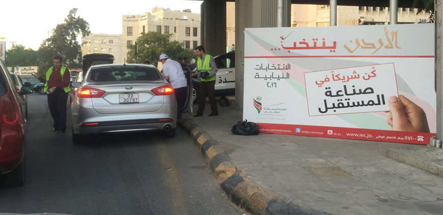 Young people distribute water and dates to help motorists break their fast on Thursday near the Interior Ministry Circle next to a sign encouraging people to vote in the upcoming elections slated for September 20 (Photo by Omar Obeidat)