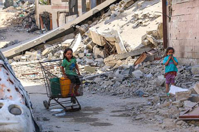 A Palestinian girl sits on a metal cart transporting water containers, in Gaza City on Monday, amid shortages of clean water during the ongoing conflict between Israel and the Palestinian Hamas fighter group (AFP Photo)