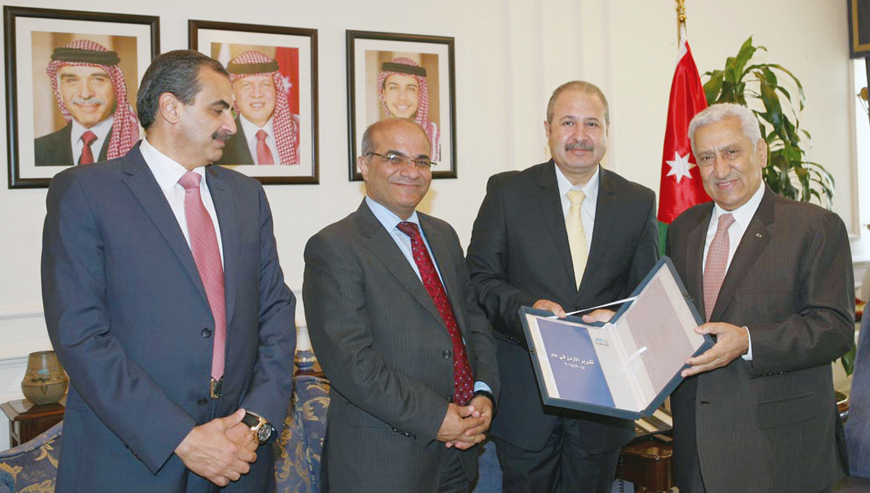 Prime Minister Abdullah Ensour receives an annual report produced by Al Rai Studies Centre from Jordan Press Foundation’s Chairman Ramadan Rawashdeh in Amman on Monday (Petra photo)