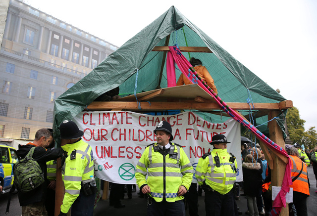 British Police officers surround a structure erected by climate change activists from the group Extinction Rebellion, during their demonstration, near Lambeth Bridge in central London, on Monday (AFP photo)