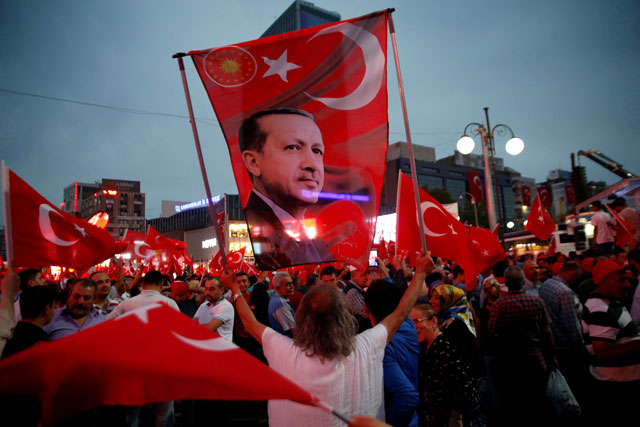 A supporter holds a flag depicting Turkish President Recep Tayyip Erdogan during a                                      pro-government demonstration in Ankara, Turkey, on July 20 (Reuters file photo)