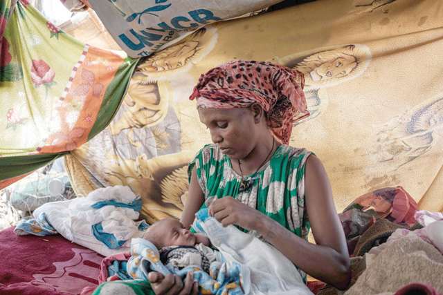 Ethiopian refugee Aster Gebremechael, 34, who fled the Ethiopia's Tigray conflict, holds her five-days-old newborn daughter in a makeshift tent at the Border Reception Centre in Hamdayit, eastern Sudan, on Friday (AFP photo)