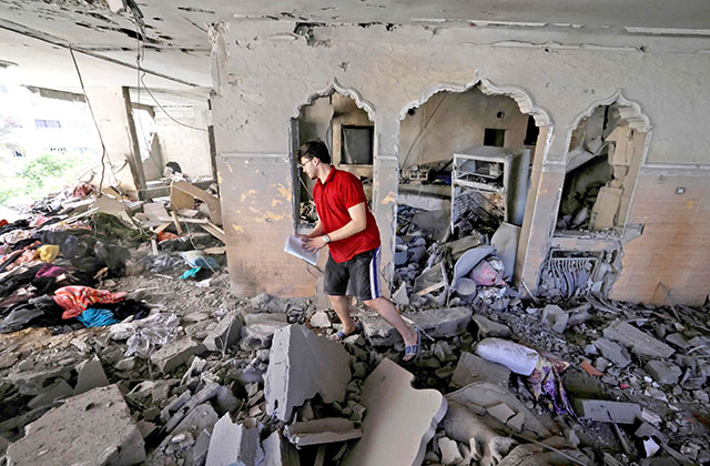A Palestinian man looks for belongings to salvage in a damaged building following Israeli air strikes in Gaza City on Saturday (AFP photo)