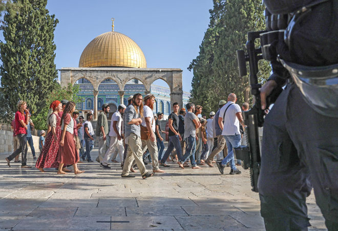 Israeli forces protect a group of Jewish settlers as they walk past the Dome of the Rock Mosque at Al Aqsa compound in Jerusalem on Sunday (AFP photo)