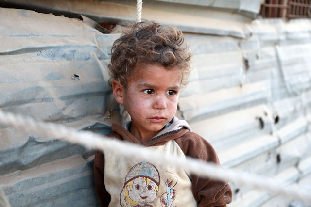 A Syrian child looks on in a heavily damaged area where his family took refuge in the rebel-held town of Saqba, in Eastern Ghouta, on Tuesday (AFP photo)