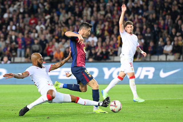 Sevilla's Brazilian defender #23 Marcao Teixeira (left) tackles Barcelona's Polish forward #09 Robert Lewandowski during the Spanish league football match between FC Barcelona and Sevilla FC at the Estadi Olimpic Lluis Companys in Barcelona on Sunday (AFP photo)