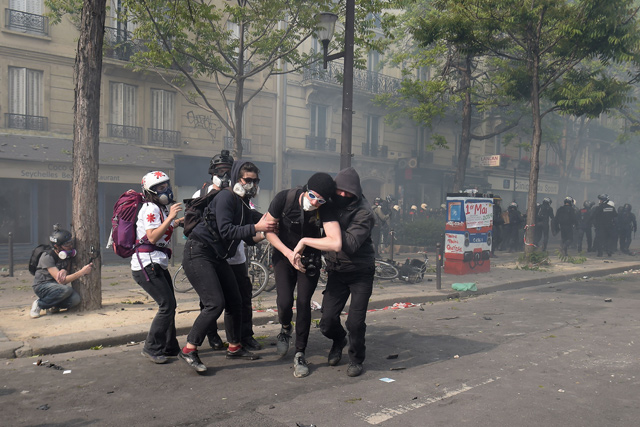 An affected protester is helped by other past a street medic during clashes with police on the sidelines of a May Day demonstration in Paris, on Wednesday (AFP photo)
