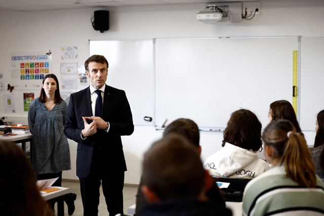 French President Emmanuel Macron gestures as he speaks with schoolchildren in a classroom during a prevention session on the papillomavirus (HPV infection) as he visits the Jean Lartaut Middle School in Jarnac, western France, on Tuesday (AFP photo)