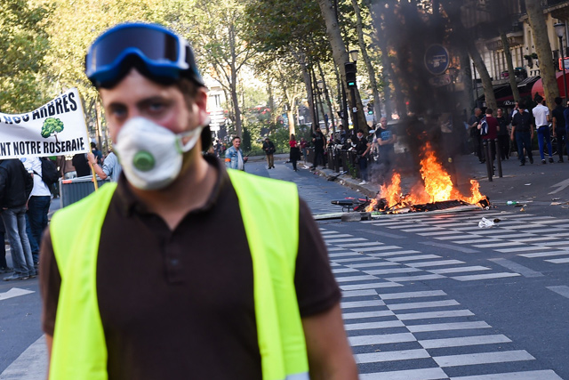 A yellow vest stands in front of burning eletric scooters during clashes with riot police as part of a climate change protest in Paris on Saturday (AFP photo)