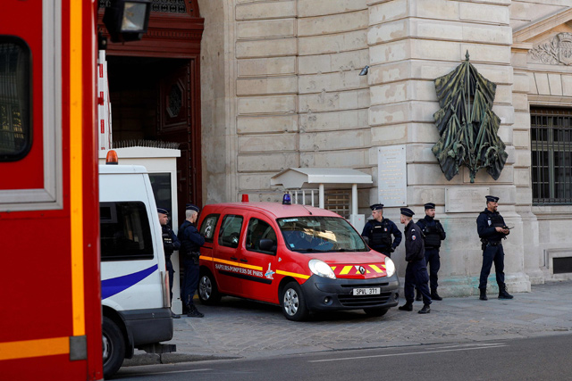Police officers watch as a firefighter truck exits Paris prefecture de police (police headquarters) on Thursday after four officers were killed in a knife attack (AFP photo)