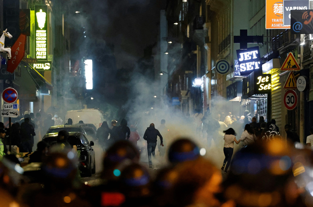 Demonstrators run as French police officers use tear gas in Paris on Sunday, after a 17-year-old man was killed by police in Nanterre, a western suburb of Paris (AFP photo)