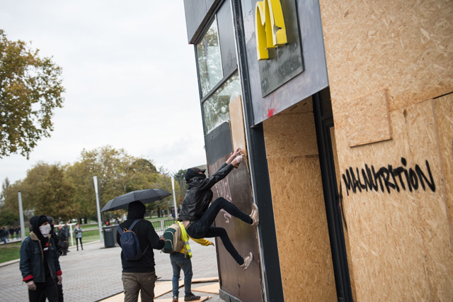 A demonstrator tries to remove a protection wood panel off the wall of a Mc Donald's restaurant on Saturday in Nantes, western France (AFP photo)